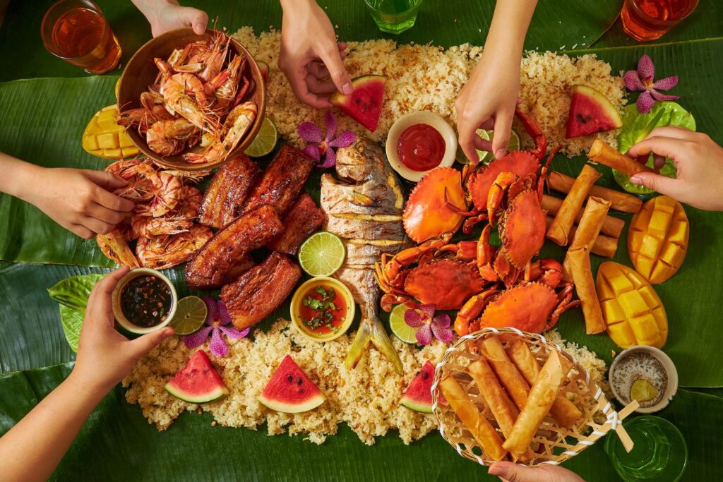 Hands reaching into a spread of Filipino seafood