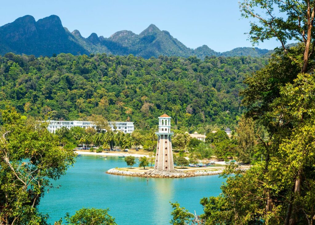 Lighthouse on a peninsula with mountains and green trees