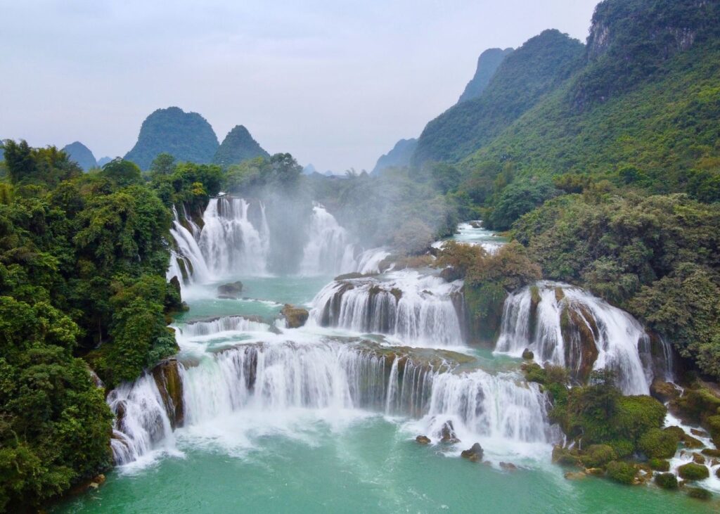 Multiple waterfalls surrounded by green mountains
