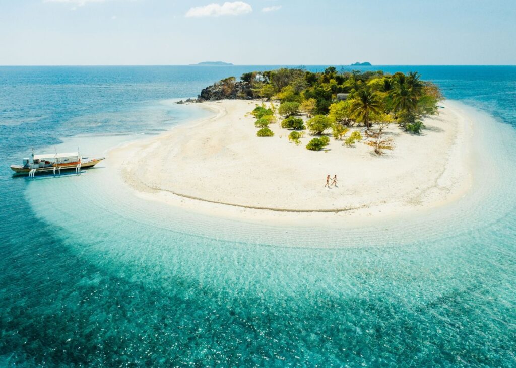 White sand round island with boat in azure waters